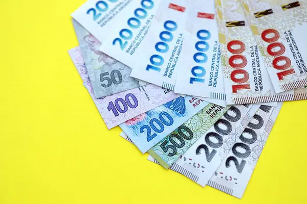 Arjantin pezosu büyük miktarlarda banknotlar sarı renkli masaya yakın duruyor. Finans ve bankacılık kavramı
