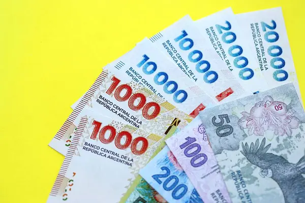 Arjantin pezosu büyük miktarlarda banknotlar sarı renkli masaya yakın duruyor. Finans ve bankacılık kavramı
