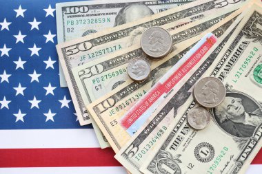 Amerikan dolarları para faturaları, Amerikan bayrağı üzerinde çalışma izni kartı. Vergi ödeme ve sigorta kavramı