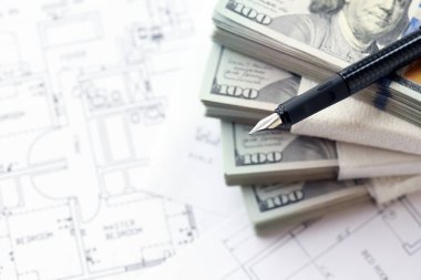 Kalemle birlikte yüklü miktarda Amerikan doları banknotları ve konut projesinin planları yakın plan. Yatırım ve inşaat projesi kavramı
