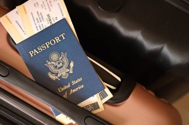 Biletlerle birlikte Amerika Birleşik Devletleri pasaportu havaalanının bekleme salonunda duran turistik bavulun üzerinde yatıyor. Dünya çapında seyahat ve uluslararası turizm kavramı