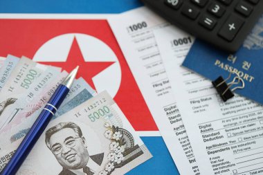 Kuzey Kore büyük miktarlarda para kazandı. Masada kalem, hesap makinesi, pasaport ve vergi formları var. Vergi ödeme ve muhasebe kavramı
