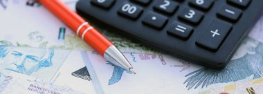 Arjantin Pezosu 'nun büyük miktarlarda para banknotları kalem ve hesap makinesiyle masanın üzerinde duruyor. Maliye ve vergi ödeme kavramı