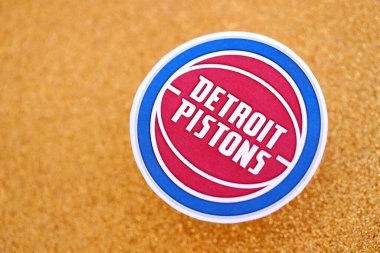 KYIV, UKRAINE - 23 Şubat 2025 Detroit Pistons basketbol takımı rozeti altın sarısı parıltılı arka plan pankartıyla yatıyor
