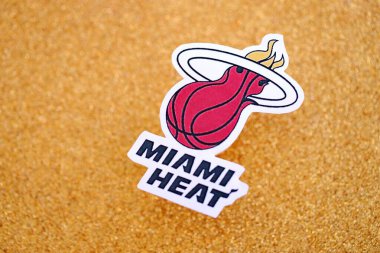 KYIV, UKRAINE - 23 Şubat 2025 Miami Heat basketbol takımı rozeti altın sarısı parıltılı arka plan afişinde yatıyor