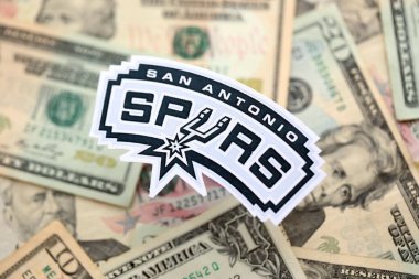 KYIV, UKRAINE - 23 Şubat 2025 San Antonio Spurs basketbol takımı rozeti Amerikan dolarlarının büyük miktarına yakın.