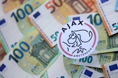KYIV, UKRAINE - 23 Şubat 2025 AFC Ajax futbol kulübü rozeti büyük miktarda EURO para banknotlarında yatıyor