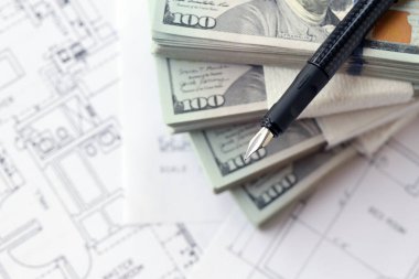 Kalemle birlikte yüklü miktarda Amerikan doları banknotları ve konut projesinin planları yakın plan. Yatırım ve inşaat projesi kavramı