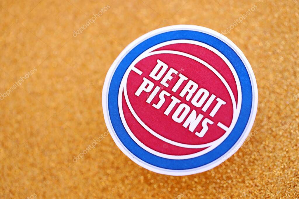 KYIV, UKRAINE - FEBRUARY 23, 2025 Detroit Pistons basketball team badge lies on golden yellow glitter background banner