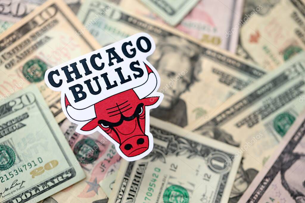 KYIV, UKRAINE - FEBRUARY 23, 2025 Chicago Bulls basketball team badge lies on big amount of US dollar bills close up