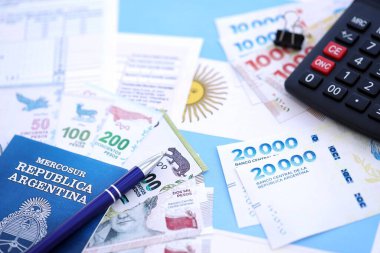 Arjantin Pezosu 'nun para faturaları kalem, hesap makinesi, pasaport ve vergi formlarıyla dolu. Finans ve bankacılık kavramı