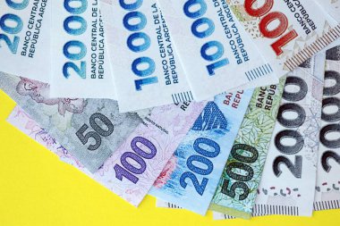 Arjantin pezosu büyük miktarlarda banknotlar sarı renkli masaya yakın duruyor. Finans ve bankacılık kavramı