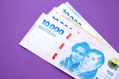 Arjantin pezosu büyük miktarda para mor renkli masaya yakın duruyor. Finans ve bankacılık kavramı