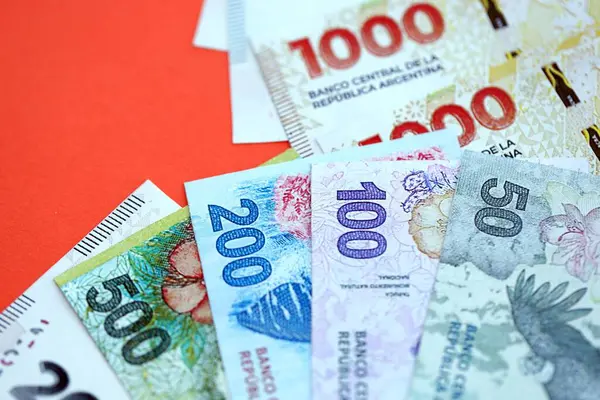 Arjantin pezosu büyük miktarlarda para kırmızı renkli masaya yakın duruyor. Finans ve bankacılık kavramı