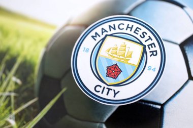 KYIV, UKRAINE - 23 Şubat 2025 Manchester FC futbol kulübü rozeti futbol arka planında yer almaktadır