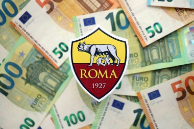 KYIV, UKRAINE - 23 Şubat 2025 Roman futbol kulübü rozeti büyük miktarda EURO para banknotlarının üzerinde yatıyor