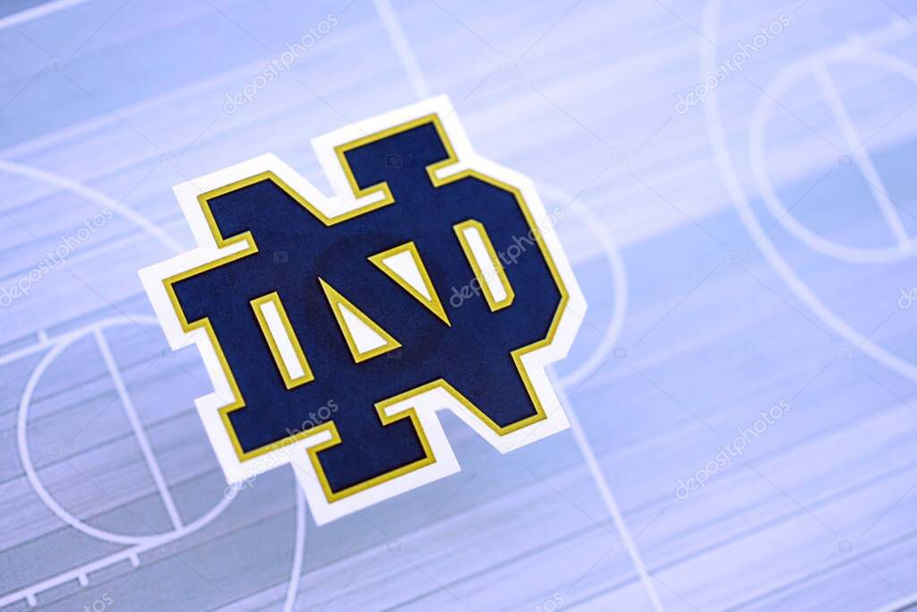 KYIV, UKRAINE - FEBRUARY 23, 2025 Notre Dame Fighting Irish basketball team badge lies on basketball stadium map background banner