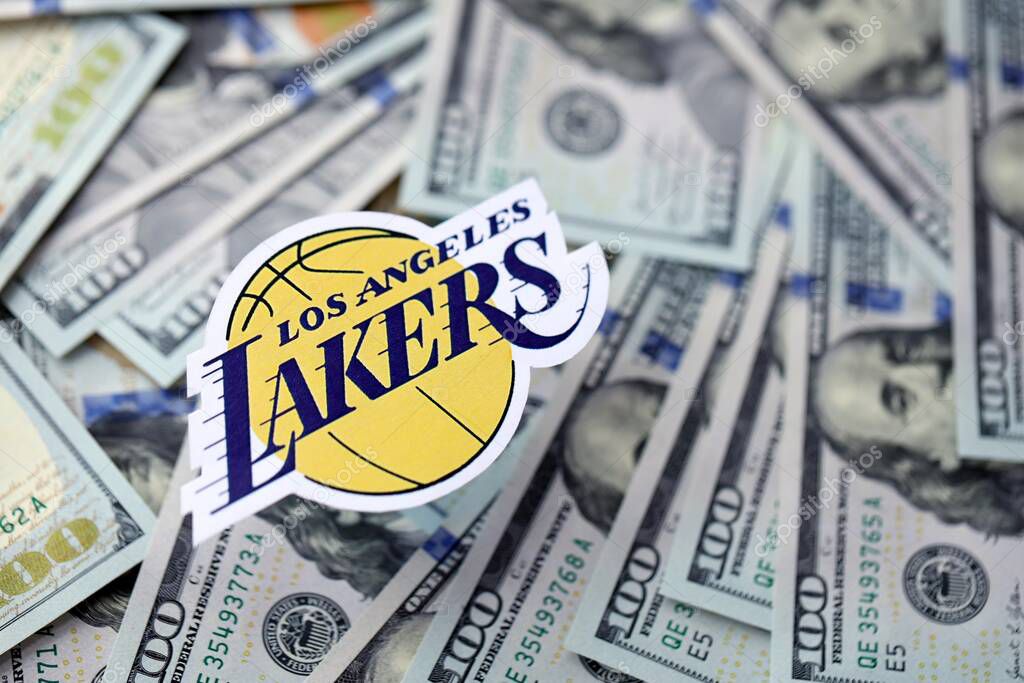 KYIV, UKRAINE - FEBRUARY 23, 2025 Los Angeles Lakers basketball team badge lies on big amount of hundred US dollar bills close up