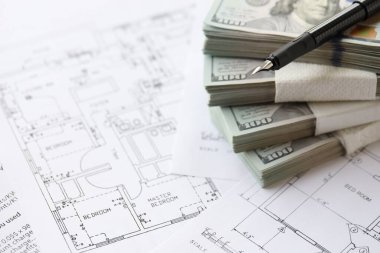 Kalemle birlikte yüklü miktarda Amerikan doları banknotları ve konut projesinin planları yakın plan. Yatırım ve inşaat projesi kavramı