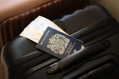 Biletli İngiliz pasaportu havaalanı bekleme salonundaki turistik bavulun üzerinde yatıyor. Dünya çapında seyahat ve uluslararası turizm kavramı