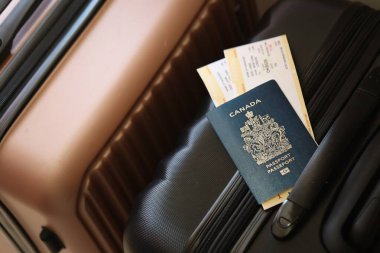 Biletli Kanada pasaportu havaalanı bekleme salonundaki turistik bavulun üzerinde yatıyor. Dünya çapında seyahat ve uluslararası turizm kavramı