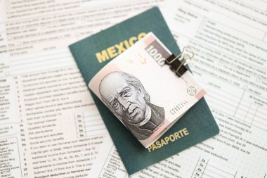 Meksika Pezosu 'nun büyük meblağlı para faturaları pasaport ve vergi formlarıyla birlikte masanın üzerinde duruyor. Maliye ve vergi ödeme kavramı