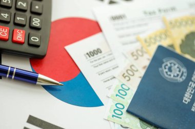 Güney Kore büyük miktarda para kazandı. Masada kalem, hesap makinesi, pasaport ve vergi formları var. Vergi ödeme ve muhasebe kavramı