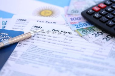 Arjantin Pezosu 'nun para faturaları kalem, hesap makinesi, pasaport ve vergi formlarıyla dolu. Finans ve bankacılık kavramı