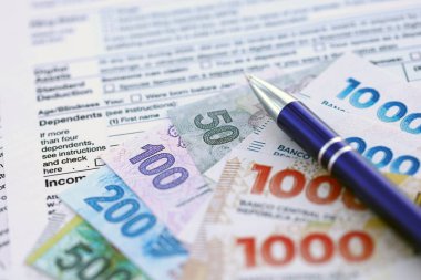 Arjantin pezosu. Büyük miktarda para. Masada, kalem ve vergi formları var.