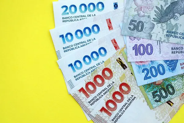 Arjantin pezosu büyük miktarlarda banknotlar sarı renkli masaya yakın duruyor. Finans ve bankacılık kavramı