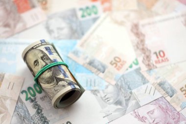 Bir tomar Amerikan doları büyük miktarda Brezilya banknotlarının üzerinde yatıyor. Amerikan parası Brezilya 'nın para akışında yatıyor. Brezilya 'da ekonomi ve döviz kuru kavramı