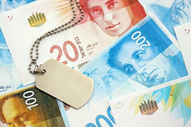 İsrail Yeni Şekelleri 'nin banknotları ve askeri simgesi. İsrail 'in mevcut para faturaları ve künyeleri büyük miktarda masada yatıyor. İsrail 'de askerlik kavramı