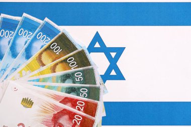 Israel New Shekels banknotları ulusal bayrak üzerinde. İsrail 'in şu anki para faturaları büyük oranda bayrağın üzerinde yatıyor. İsrail 'de iş ve yatırım kavramı