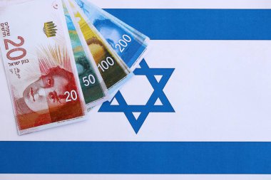 Israel New Shekels banknotları ulusal bayrak üzerinde. İsrail 'in şu anki para faturaları büyük oranda bayrağın üzerinde yatıyor. İsrail 'de iş ve yatırım kavramı