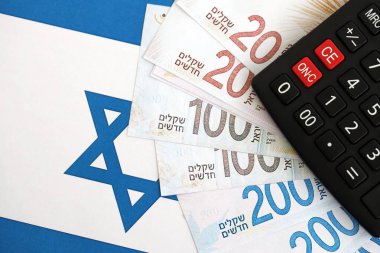 Israel New Shekels banknotları ve hesap makinesi bayrağın üzerinde. İsrail 'in mevcut para faturaları ve kalibreleri büyük oranda bayrakta yatıyor. İsrail 'de vergilendirme ve para kavramı