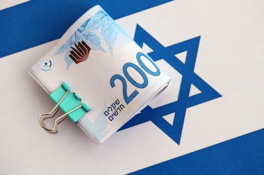 Israel New Shekels banknotları ulusal bayrak üzerinde. İsrail 'in şu anki para faturaları büyük oranda bayrağın üzerinde yatıyor. İsrail 'de iş ve yatırım kavramı