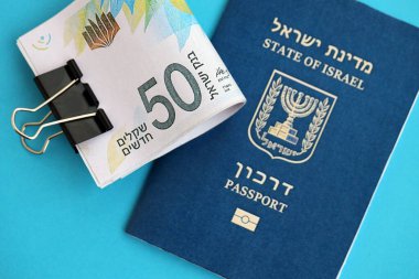 Israel New Shekels banknotları ve mavi arka planda pasaport. İsrail 'in şu anki para banknotları büyük oranda mavi üzerine yatar. İsrail 'de finans ve nakit kavramı