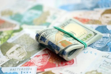 Amerikan dolarları yığını Pakistan Rupi banknotlarının büyük bir miktarına yakın duruyor. Amerikan para demeti Pakistan 'ın para banknotlarında yatıyor. Pakistan 'da ekonomi ve döviz kuru kavramı