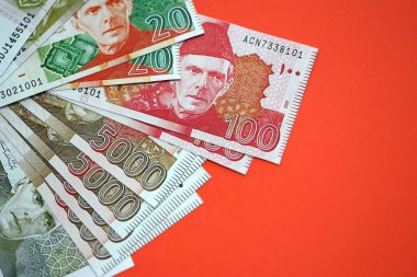 Pakistan kırmızı arka planda banknotlar halinde. Pakistan 'ın mevcut para faturaları büyük miktarda masada yatıyor. Pakistan 'da iş ve yatırım kavramı