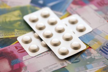 İsviçre frangı ve ilaç hapları. Mevcut para ve uyuşturucu banknotları büyük miktarda masada yatıyor. İsviçre 'de ilaç ve eczane kavramı