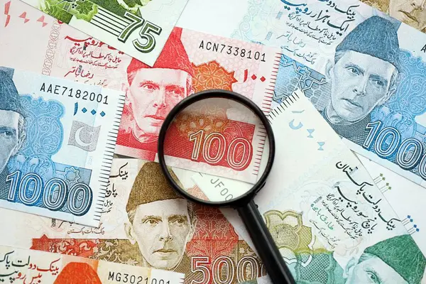 Pakistan banknotları ve büyüteç. Pakistan 'ın mevcut para ve büyüteç faturaları büyük miktarda masanın üzerinde duruyor. Pakistan 'da mali izleme ve vergilendirme kavramı