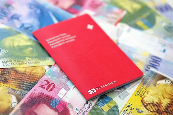İsviçre frangı banknotları ve pasaportu. Mevcut banknotlar ve biyometrik geçiş kartları büyük miktarda masada yatıyor. İsviçre 'de seyahat ve tatil kavramı