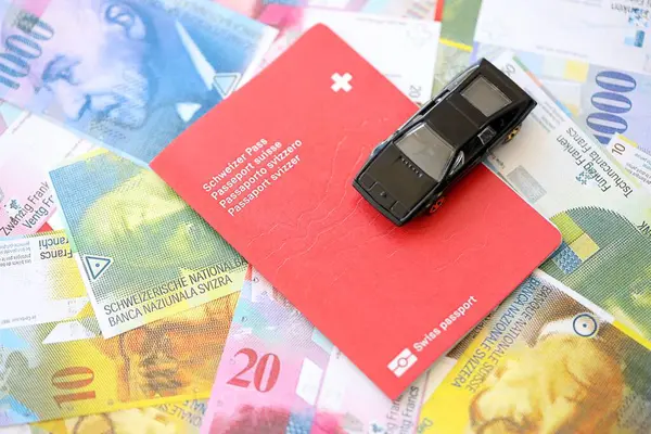 İsviçre frangı banknotları ve pasaportlu oyuncak araba. Mevcut frank, faturalar ve geçiş kartı olan siyah araba büyük miktarda masada yatıyor. İsviçre 'de araba sahibi olma kavramı