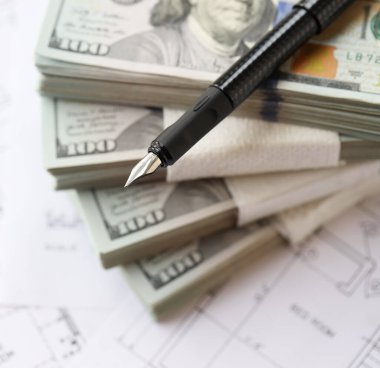 Kalemle birlikte yüklü miktarda Amerikan doları banknotları ve konut projesinin planları yakın plan. Yatırım ve inşaat projesi kavramı