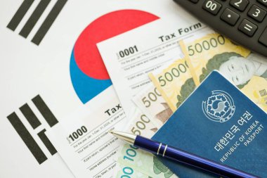 Güney Kore büyük miktarda para kazandı. Masada kalem, hesap makinesi, pasaport ve vergi formları var. Vergi ödeme ve muhasebe kavramı