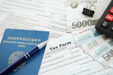 Kuzey Kore büyük miktarlarda para kazandı. Masada kalem, hesap makinesi, pasaport ve vergi formları var. Vergi ödeme ve muhasebe kavramı