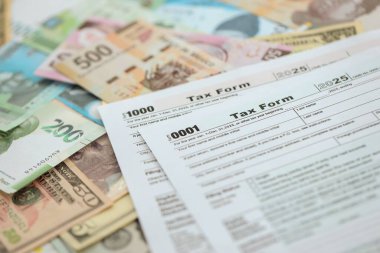 Değişik para birimlerinden ve ülkelerden oluşan büyük miktarlarda para ve vergi beyannamesi doldurulmaya hazır. Uluslararası nakitin çeşitli arka planında büyük bir yığın var.