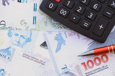 Arjantin pezosu. Büyük miktarda para. Masada, kalem ve hesap makinesi ile birlikte.