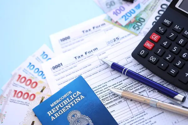 Arjantin Pezosu 'nun para faturaları kalem, hesap makinesi, pasaport ve vergi formlarıyla dolu. Finans ve bankacılık kavramı