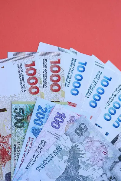 Arjantin pezosu büyük miktarlarda para kırmızı renkli masaya yakın duruyor. Finans ve bankacılık kavramı